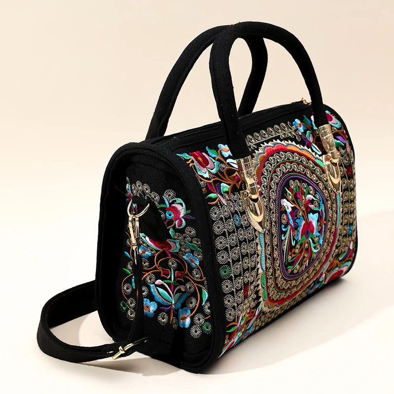 Bolsa Boho Mandala com estampa de mandala, alças pretas e detalhes em tecido, posicionada sobre fundo bege.