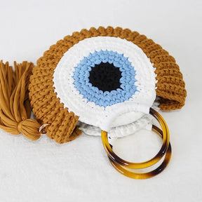 Bolsa Olho Grego na cor mostarda, feita em crochê sintético com alça plástica, ideal para proteção e estilo.